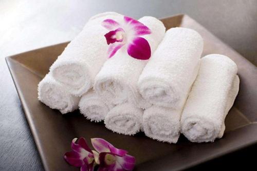 a pile of towels on a plate with a flower at Fenggang Gladden Hotel in Tiantangwei