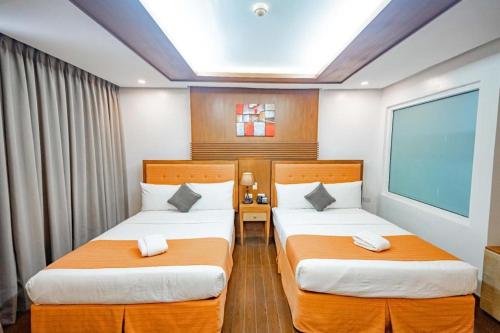 two beds in a hotel room with a window at Subic Grand Harbour Hotel Subic Bay in Olongapo