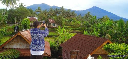 a woman taking a picture of a house at Ariel Bungalow Tetebatu in Tetebatu