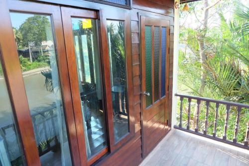 a balcony with wooden doors on a house at River Jam Amphawa in Amphawa