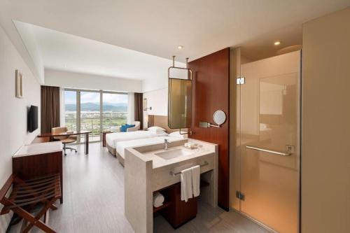a hotel room with a bed and a sink and a bathroom at Grand Soluxe Hotel and Resort Sanya in Sanya