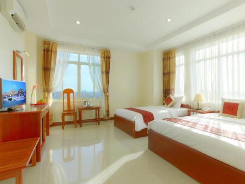 a hotel room with two beds and a desk and window at Kirirom Crystal Hotel in Phnom Penh