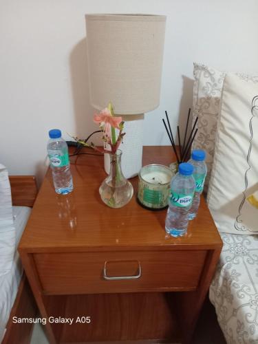 a nightstand with two bottles of water and a lamp at ESPERANZA Pension House & Restaurant in Roxas