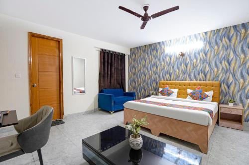 a bedroom with a bed and a blue chair at FabHotel Divine & Banquet in Noida