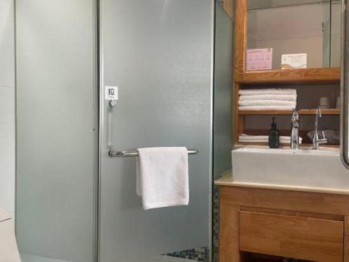 a bathroom with a shower with a sink and a towel at Beijing Inner Mongolia Hotel Chaoyang in Beijing