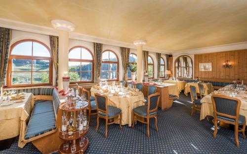 uma sala de jantar com mesas, cadeiras e janelas em Hotel Alpenflora em Castelrotto