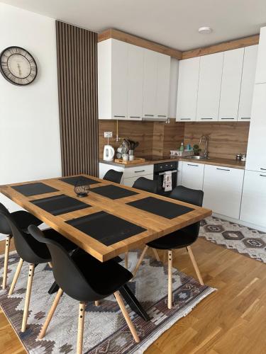 a kitchen with a wooden table and black chairs at ZORA apartmani Sarajevo in Sarajevo