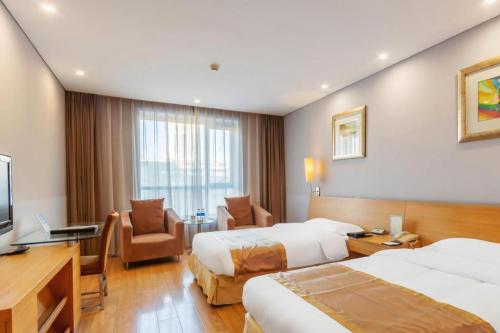 a hotel room with two beds and a desk at Tangshan Qiangang Hotel in Qian'an