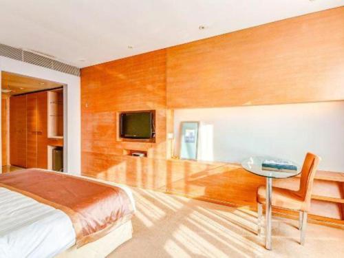 a bedroom with a bed and a table and a tv at Tangshan Qiangang Hotel in Qian'an