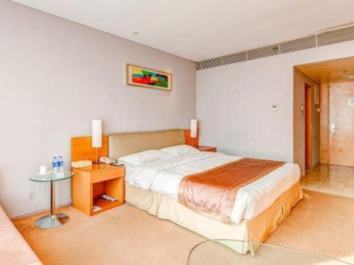 a bedroom with a large bed and a table at Tangshan Qiangang Hotel in Qian'an