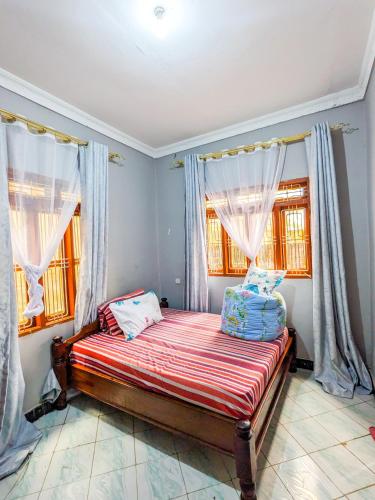 Un dormitorio con una cama en una habitación con ventanas. en Karibu Jua Backpackers Hostel, en Mbeya