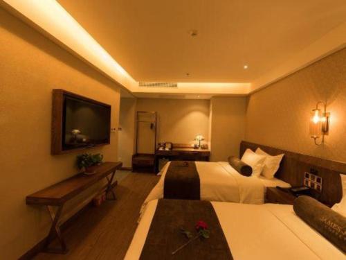 a hotel room with two beds and a flat screen tv at James Joyce Coffetel Tianjin Railway Station Jinshiqiao Metro Station Branch in Tianjin