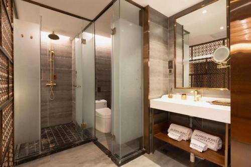 a bathroom with a shower and a sink and a mirror at James Joyce Coffetel Tianjin Railway Station Jinshiqiao Metro Station Branch in Tianjin