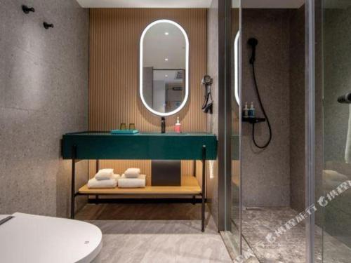 a bathroom with a green sink and a mirror at City Comfort Inn Guangzhou Baiyun Mountain in Guangzhou