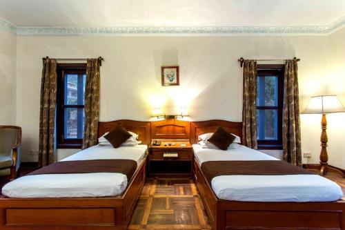two beds in a room with two windows at Godavari Village Resort in Kathmandu