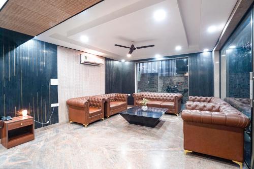 a living room with leather couches and a table at FabHotel Divine & Banquet in Noida