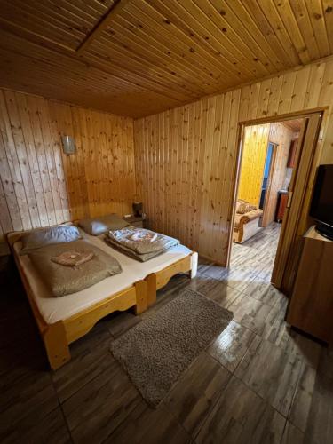 a bedroom with a bed in a wooden room at Sunny Faház in Poroszló