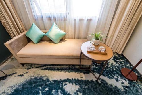 a room with a couch with a table and a window at Fliport Garden Hotel Nanjing in Nanjing