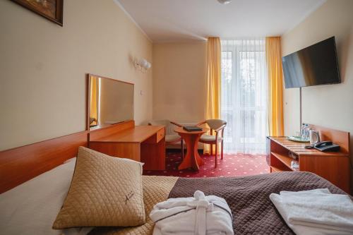 a hotel room with a bed and a desk at Kompleks Antałówka Termy & Med in Zakopane
