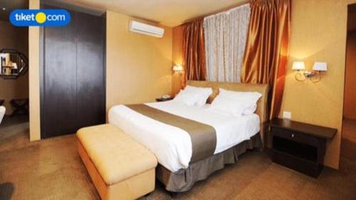 a hotel room with a large bed and a chair at Kenari Tower Hotel in Makassar