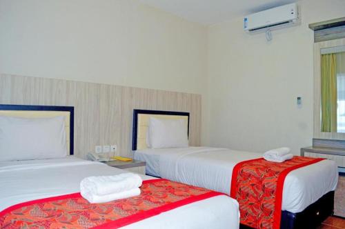 a hotel room with two beds with red accents at Grant Hotel Subang in Bandung