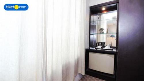 a room with a mirror and a window and a curtain at Kenari Tower Hotel in Makassar