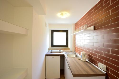 uma cozinha com um lavatório e uma parede de tijolos em Apartament Na Górskiej em Szczyrk