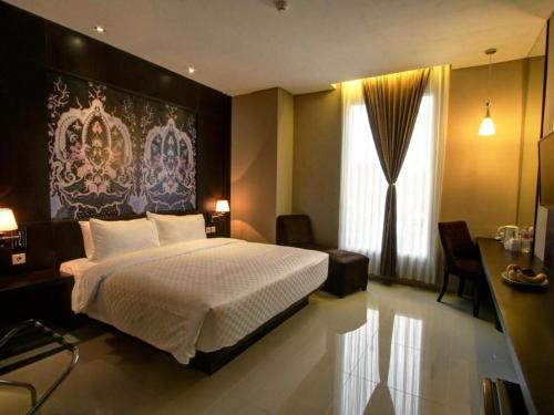 a bedroom with a bed and a large painting on the wall at Hotel Betha Subang in Bandung