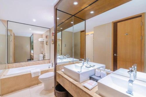 a bathroom with two sinks and a toilet and mirrors at Great International Hotel in Heyuan