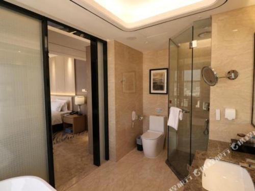 a bathroom with a shower and a toilet and a sink at Clear Lake Hotel in Shanwei