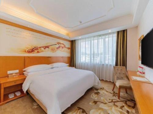 a bedroom with a bed and a desk and a television at Out Sky Hotel in Huizhou