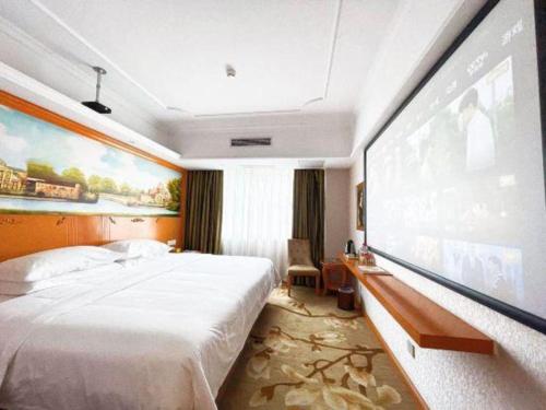 a hotel room with a large bed and a large screen at Out Sky Hotel in Huizhou
