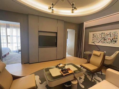 a living room with a couch and a table and a tv at Clear Lake Hotel in Shanwei