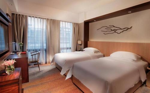 a hotel room with two beds and a television at Great International Hotel in Heyuan