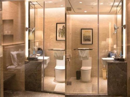 a bathroom with two toilets and a sink and a shower at Clear Lake Hotel in Shanwei