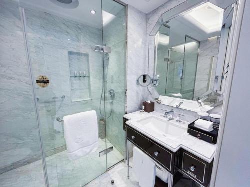 a bathroom with a glass shower and a sink at Xian Jue Vu Hotel in Xi'an