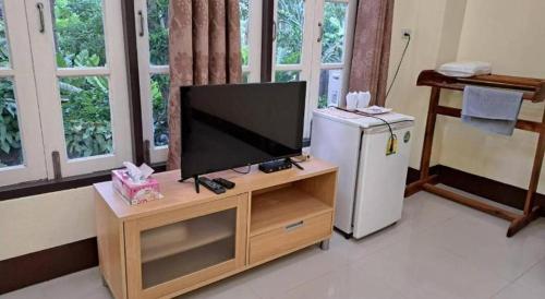 a television on a stand in a living room with a refrigerator at At Home Suanphung in Ratchaburi