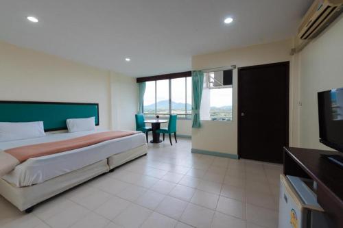 a bedroom with a bed and a table and a television at Nice Beach Hotel in Rayong