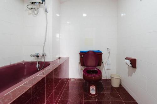 a bathroom with a red toilet and a bath tub at Nice Beach Hotel in Rayong
