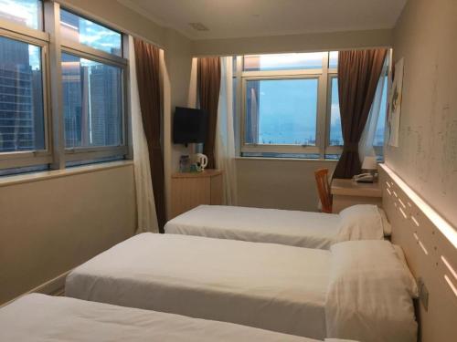 a hotel room with two beds and two windows at West Hotel in Hong Kong
