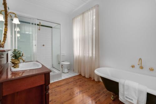 a white bathroom with a tub and a sink at Studio Cottage Alpine Southern Highlands in Alpine