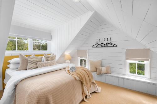 a white bedroom with a large bed and windows at Studio Cottage Alpine Southern Highlands in Alpine
