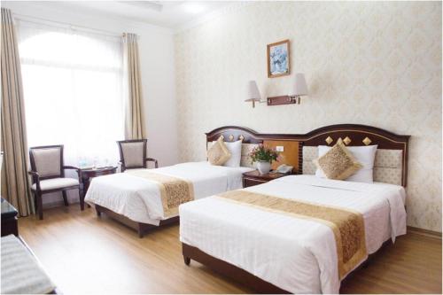 a hotel room with two beds and a table and chairs at Cong Doan Viet Nam Hotel in Hanoi