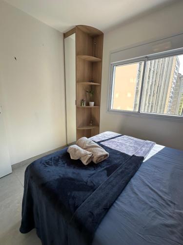 a bedroom with a bed with a blue blanket and a window at Apto Completo, 3min Estação Higienópolis Mackenzie Consolação in Sao Paulo