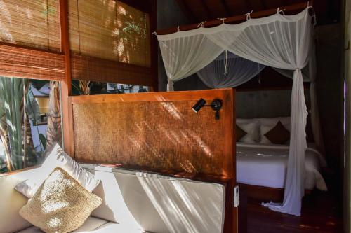 a room with a bed with a canopy and a toilet at ZIN Berawa Villas & Bungalows in Canggu