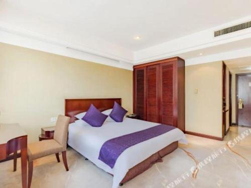 a bedroom with a large bed and a chair at Dajiuhua Hotel in Chizhou