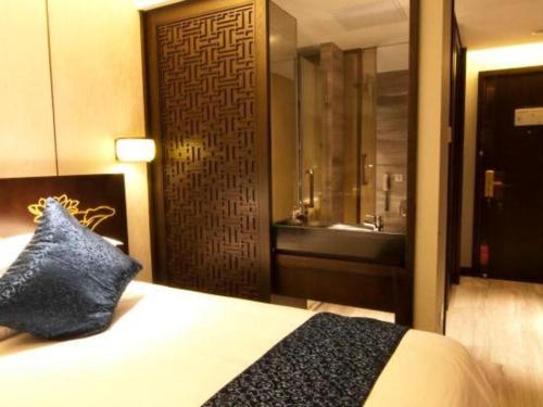 a bedroom with a bed and a bathroom with a shower at Dajiuhua Hotel in Chizhou