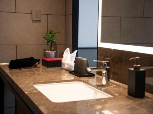 a bathroom counter with a sink and a mirror at Dajiuhua Hotel in Chizhou