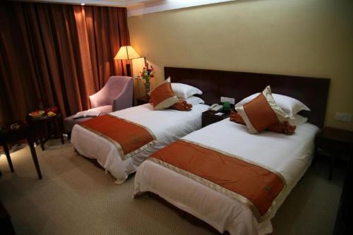 a hotel room with two beds and a chair at Dajiuhua Hotel in Chizhou