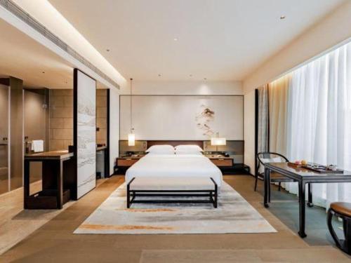 a bedroom with a large bed and a desk at Dajiuhua Hotel in Chizhou